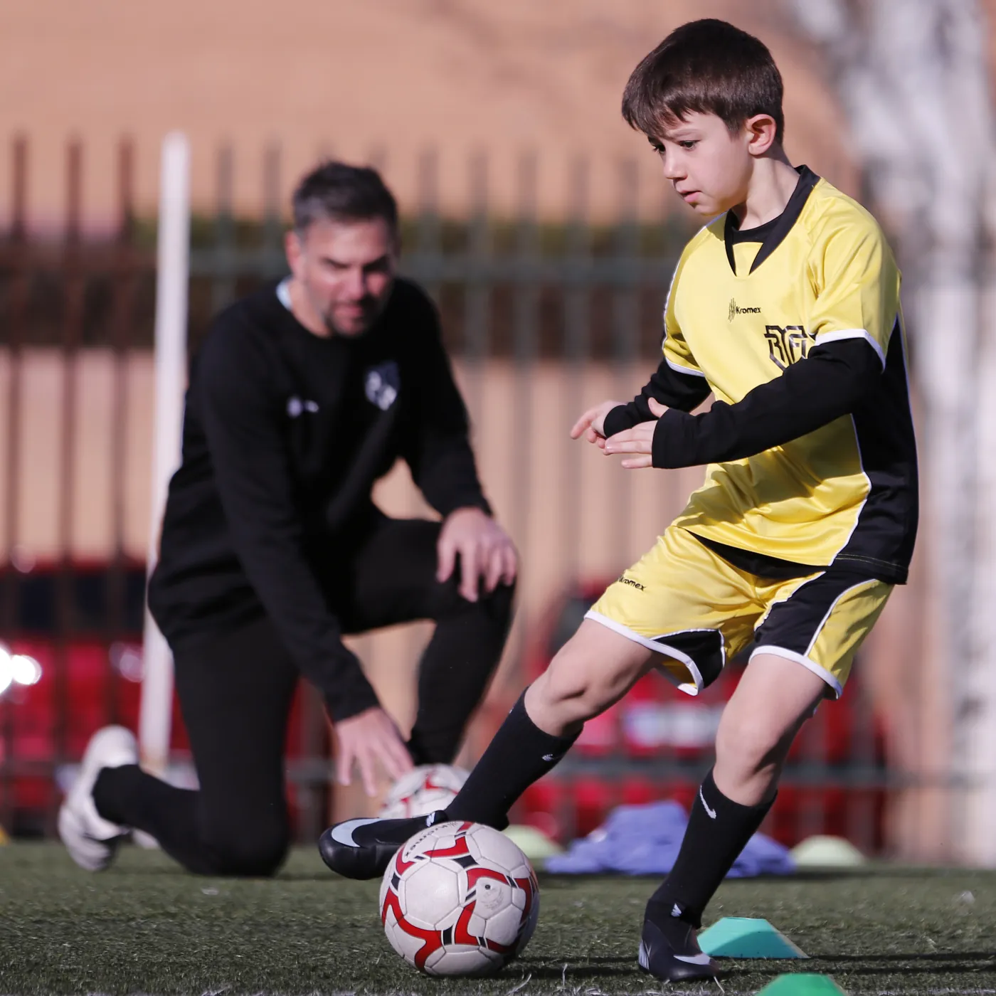 Corrección individual en MR Fútbol Entrenador de MR Fútbol observando y corrigiendo a un jugador durante un ejercicio